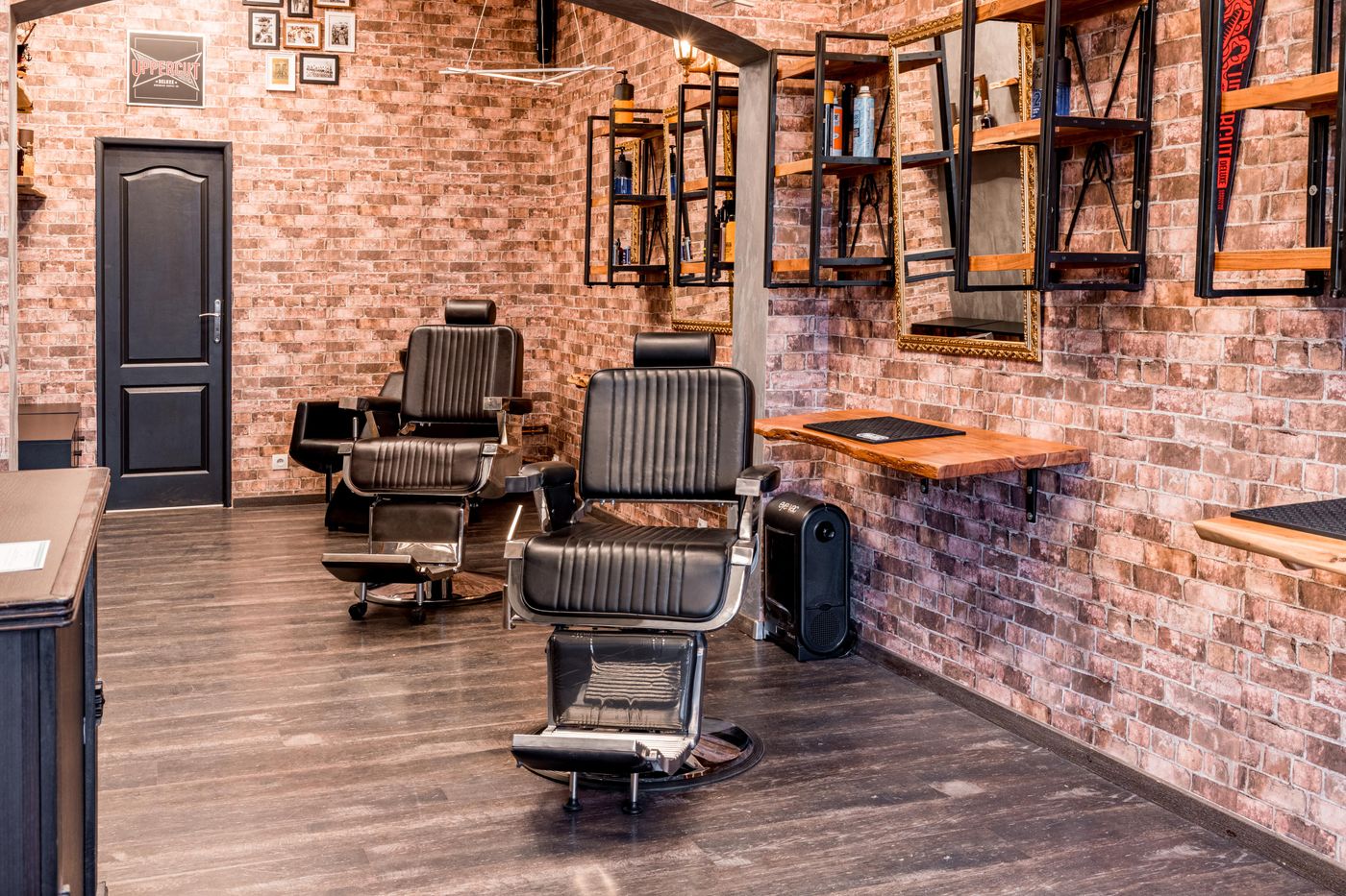 Salon de barbier aux murs de briques, fauteuils en cuir noir