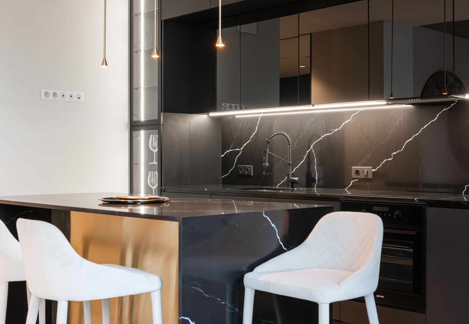 Cuisine noire avec crédence en marbre veiné et îlot sur mesure