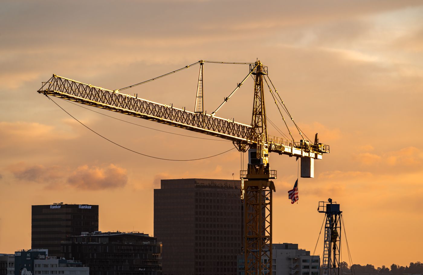 Grue à tour au-dessus d'immeubles en construction au coucher du soleil