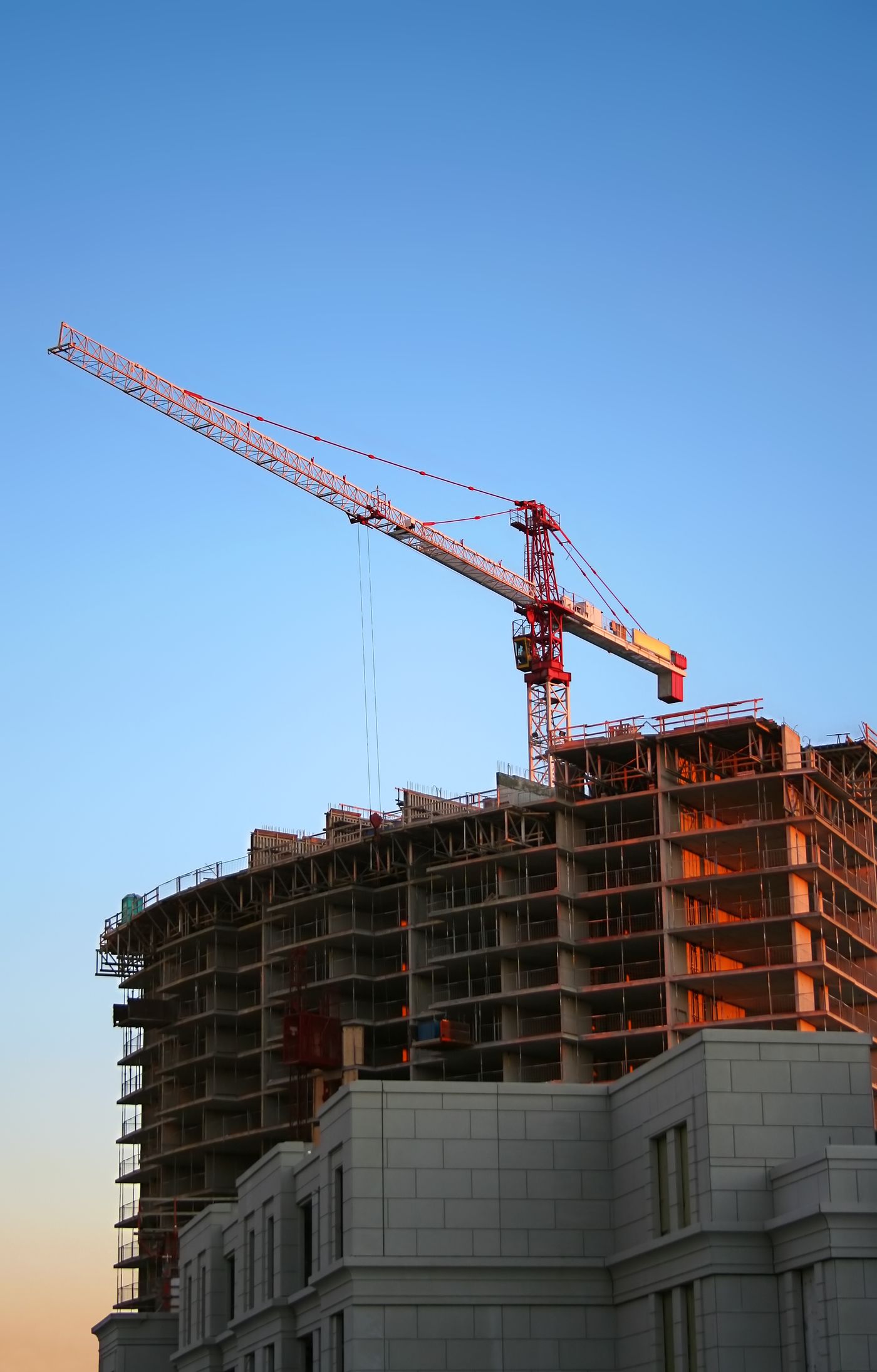 Immeuble en construction avec une grue à tour sous un ciel bleu