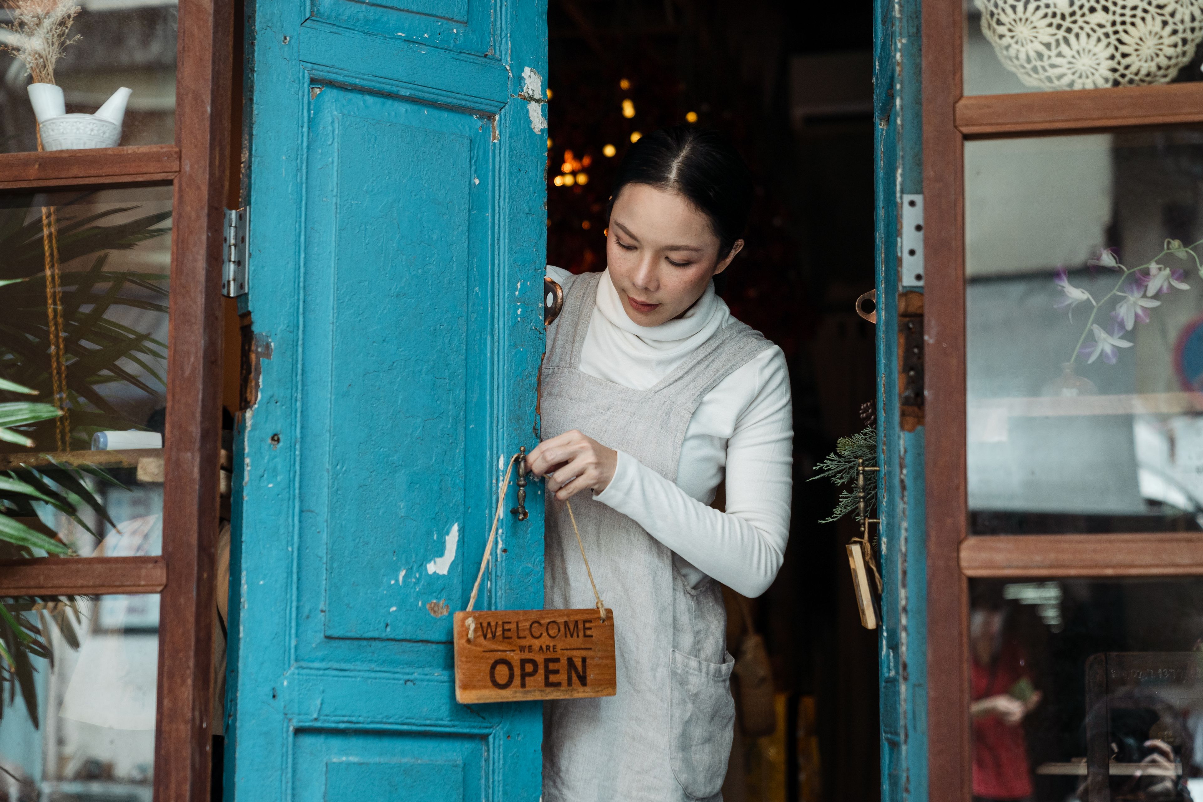 Une commerçante règle l'écriteau Open sur la porte bleue de son café