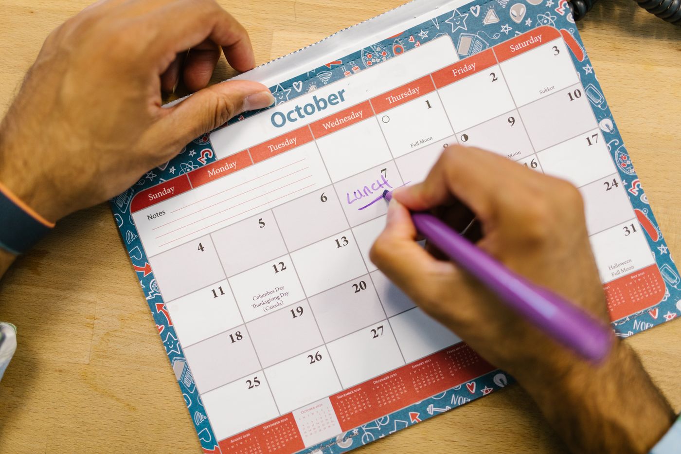 Une main entoure une date sur un calendrier papier